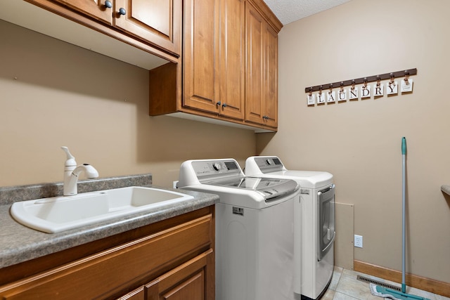 washroom with light tile patterned floors, cabinet space, a sink, a textured ceiling, and washer and dryer