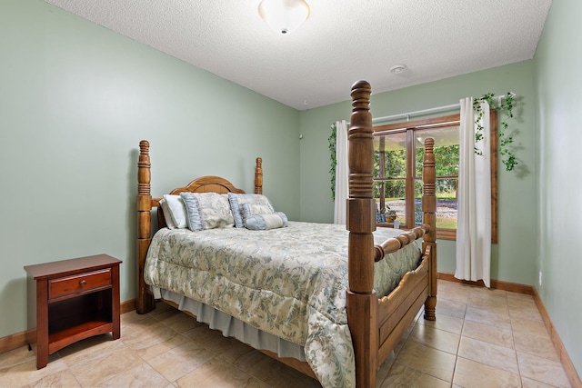 bedroom featuring a textured ceiling, light tile patterned floors, and baseboards