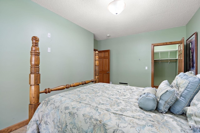 bedroom with a textured ceiling, a closet, a walk in closet, and baseboards