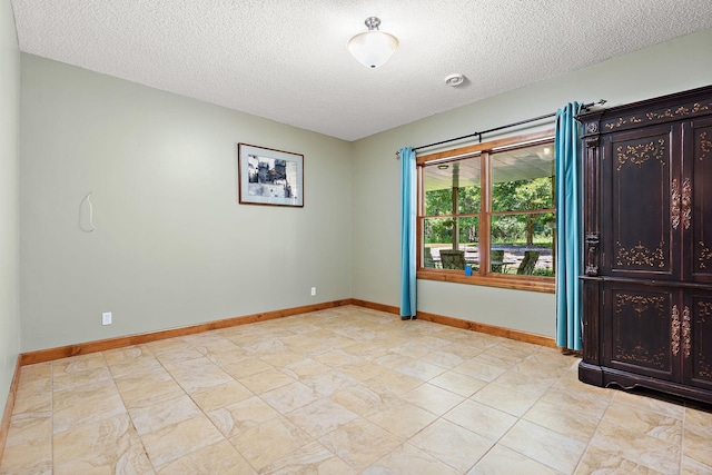 spare room with a textured ceiling and baseboards