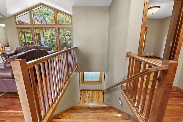 staircase with high vaulted ceiling and wood finished floors