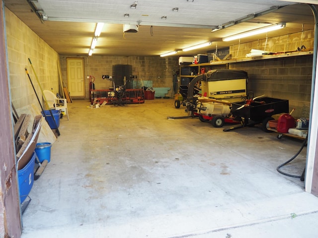 garage featuring a garage door opener and concrete block wall