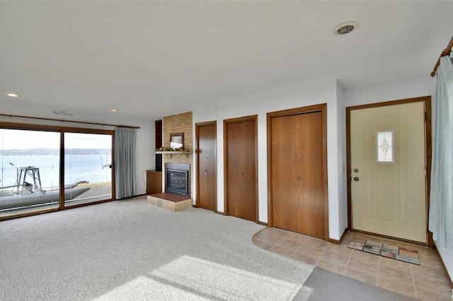 unfurnished living room with a brick fireplace, recessed lighting, and light colored carpet