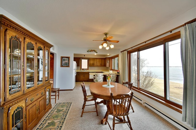 dining area featuring light carpet, baseboards, a baseboard heating unit, and ceiling fan