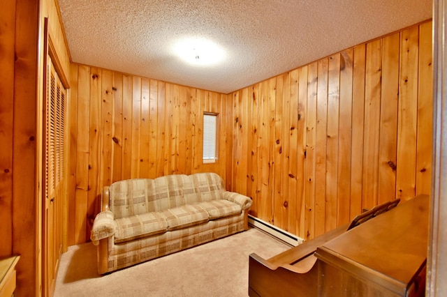 living room featuring a baseboard heating unit, carpet flooring, wood walls, and a textured ceiling