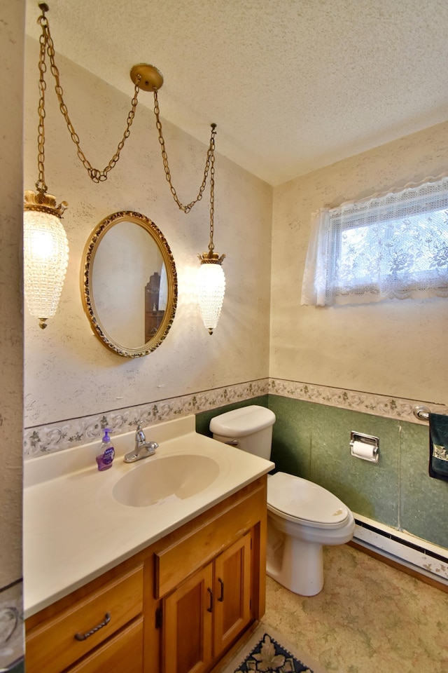 half bath with toilet, vanity, a textured ceiling, tile walls, and a baseboard radiator