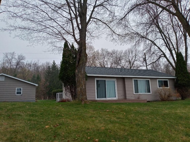 rear view of property with a yard and roof with shingles