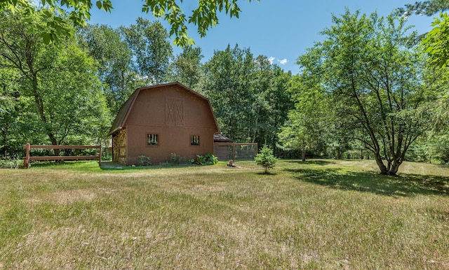 view of yard featuring a barn, fence, and an outbuilding