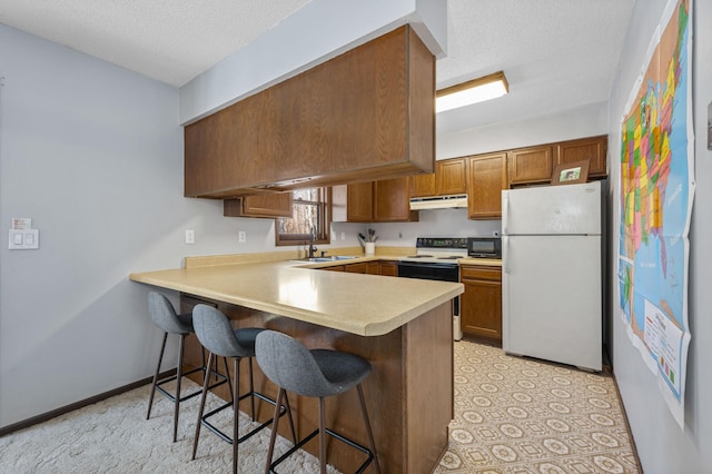 kitchen featuring electric stove, freestanding refrigerator, a peninsula, black microwave, and under cabinet range hood