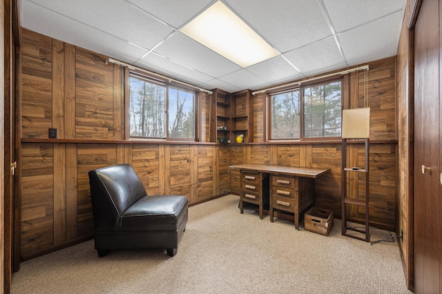 home office featuring a paneled ceiling, wood walls, and light colored carpet