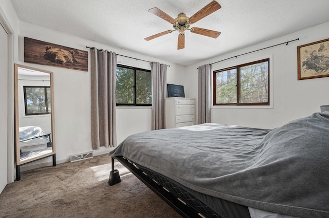 bedroom featuring a textured ceiling, multiple windows, visible vents, and carpet flooring