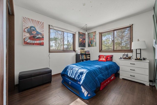 bedroom with a textured ceiling, dark wood-style flooring, and baseboards