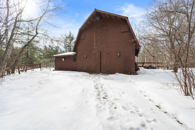 snow covered property with an outbuilding, a barn, a gambrel roof, and a garage