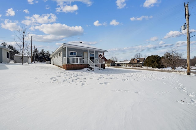 snow covered property with covered porch