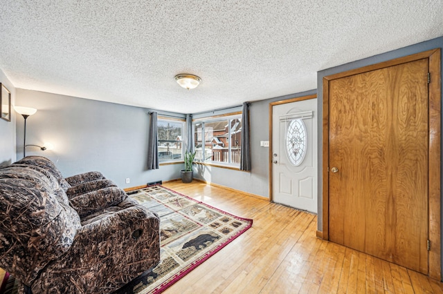 foyer entrance with a textured ceiling, baseboards, and hardwood / wood-style floors