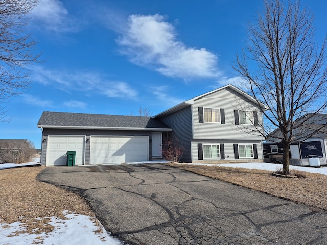 split level home featuring a garage, driveway, and a shingled roof