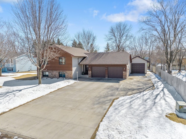 view of front of house with brick siding, fence, roof with shingles, a garage, and driveway