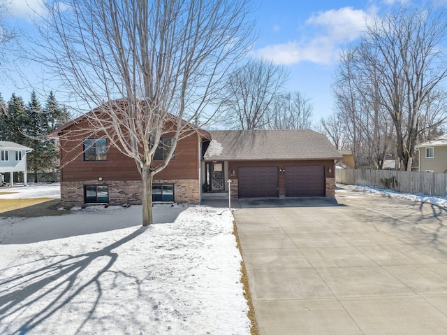 view of front facade featuring brick siding, a shingled roof, fence, a garage, and driveway