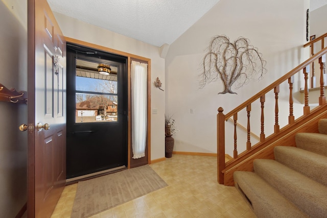 entryway with lofted ceiling, a textured ceiling, baseboards, light floors, and stairs