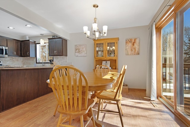 dining space with light wood-style flooring and a notable chandelier