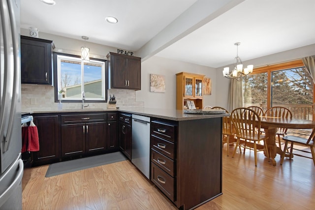 kitchen with a peninsula, a healthy amount of sunlight, light wood-style floors, and stainless steel appliances