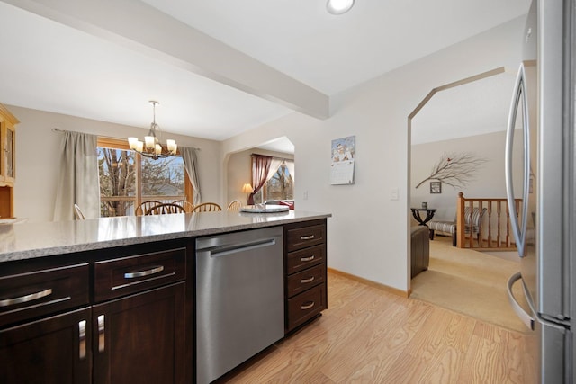 kitchen featuring light wood finished floors, a chandelier, beamed ceiling, appliances with stainless steel finishes, and arched walkways