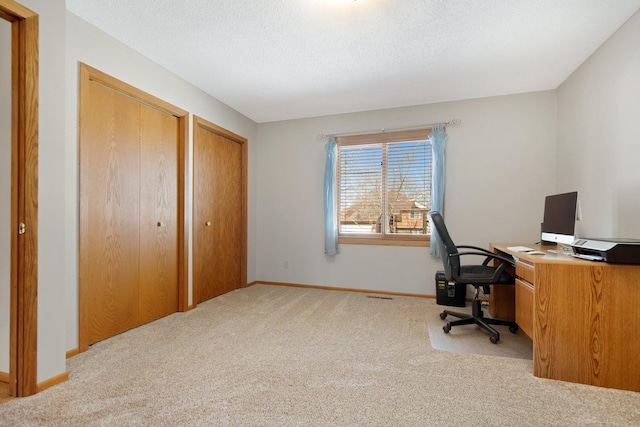 carpeted office space featuring visible vents, baseboards, and a textured ceiling