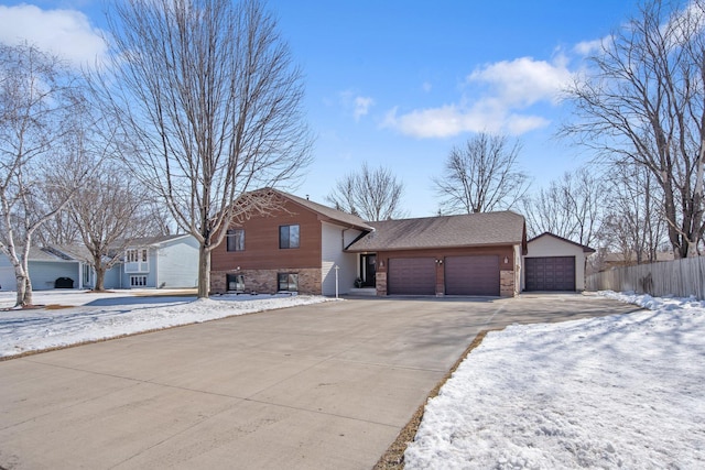 view of front facade with driveway, brick siding, an attached garage, and fence