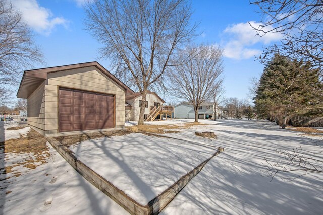 yard covered in snow featuring an outbuilding and a garage