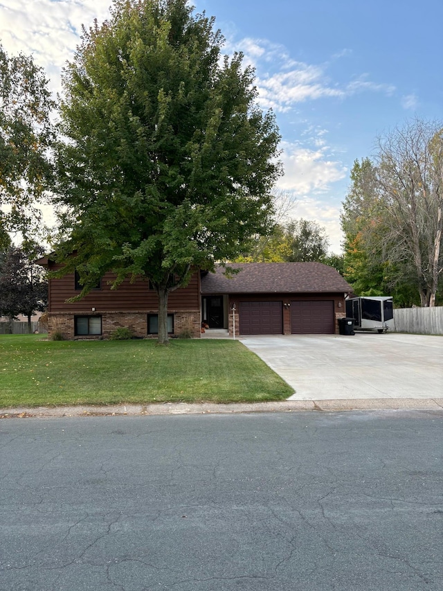 view of front of property with a front lawn, fence, roof with shingles, concrete driveway, and an attached garage