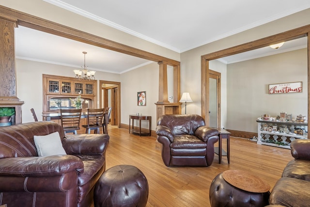 living room featuring crown molding, decorative columns, baseboards, and light wood finished floors