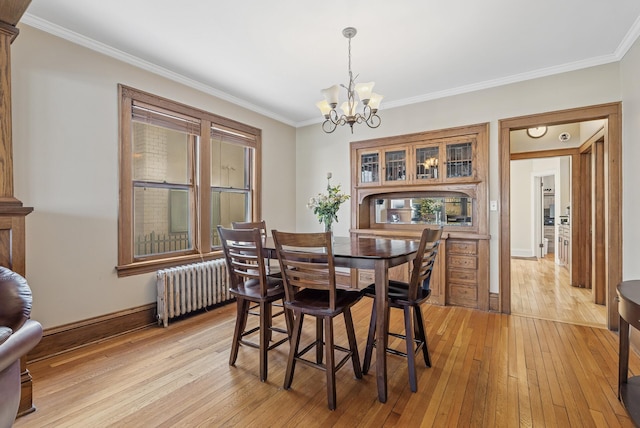 dining room with light wood-style flooring, radiator, a chandelier, and ornamental molding