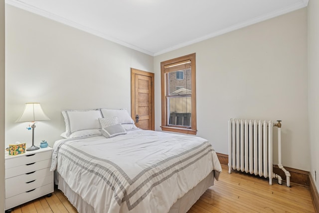 bedroom with light wood-style flooring, radiator heating unit, baseboards, and ornamental molding