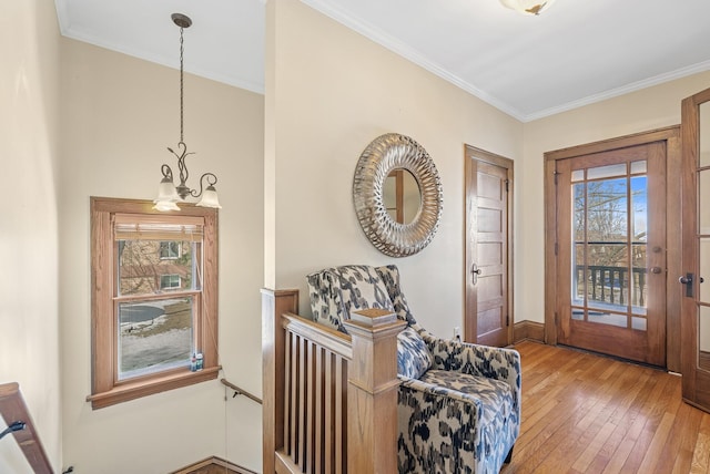 entrance foyer featuring a chandelier, a healthy amount of sunlight, crown molding, and wood-type flooring