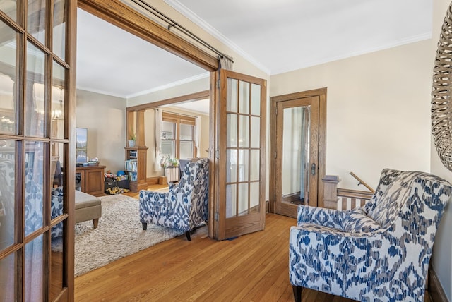 living area with wood finished floors, french doors, and ornamental molding