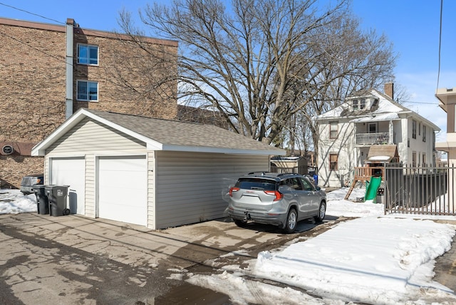 view of side of property featuring an outbuilding, a shingled roof, a detached garage, and a playground