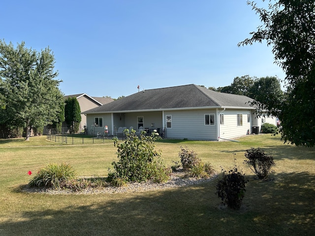 back of property featuring fence and a lawn