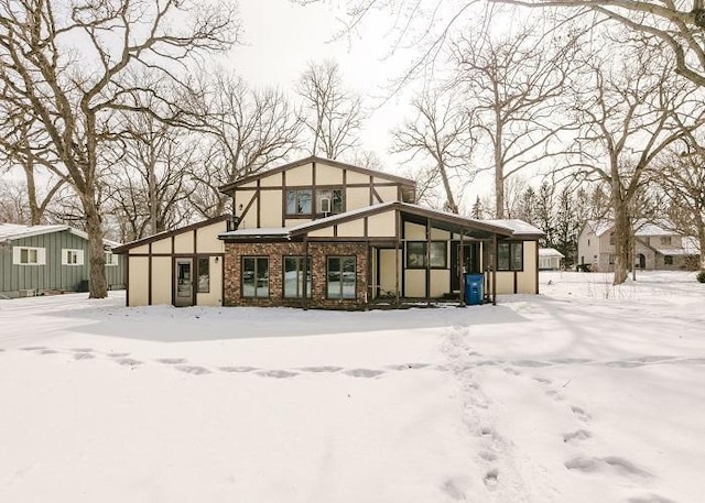 snow covered house featuring brick siding