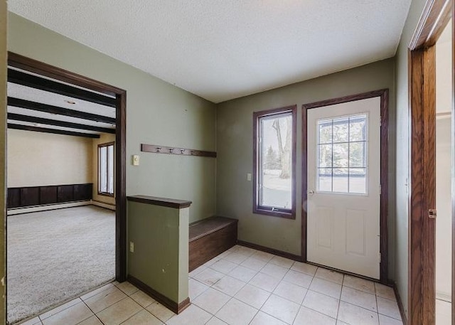 doorway with light carpet, light tile patterned flooring, a textured ceiling, beamed ceiling, and baseboards