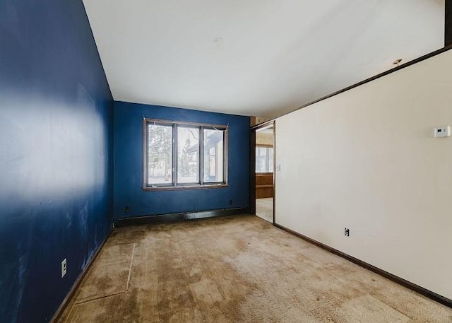 carpeted empty room featuring baseboards