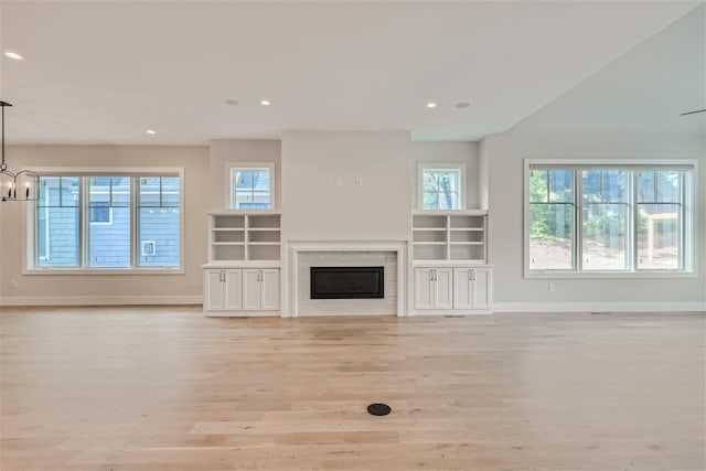 unfurnished living room with light wood-style floors, a glass covered fireplace, baseboards, and recessed lighting
