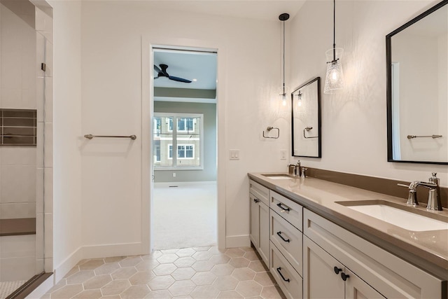 full bath with a sink, a tile shower, baseboards, and double vanity