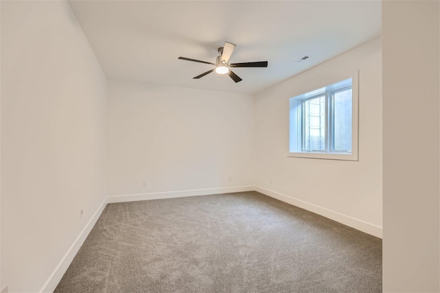 unfurnished room with a ceiling fan, dark colored carpet, visible vents, and baseboards