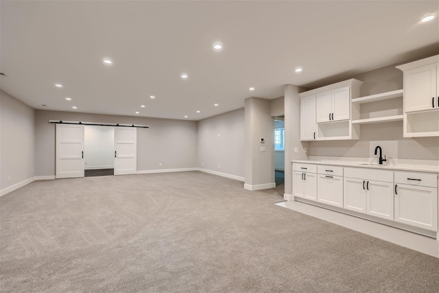 unfurnished living room featuring recessed lighting, light carpet, a sink, and a barn door