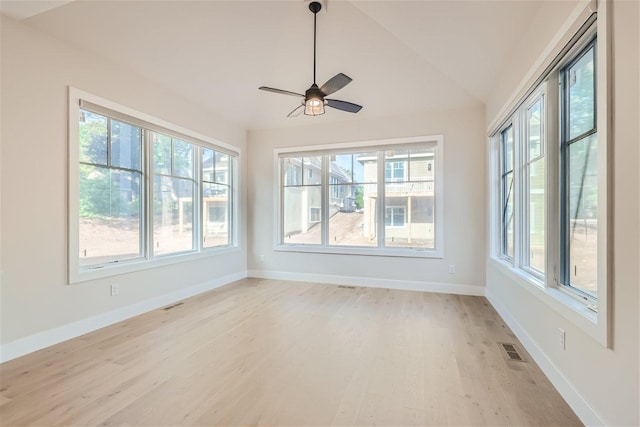 unfurnished room with vaulted ceiling, light wood finished floors, visible vents, and a healthy amount of sunlight