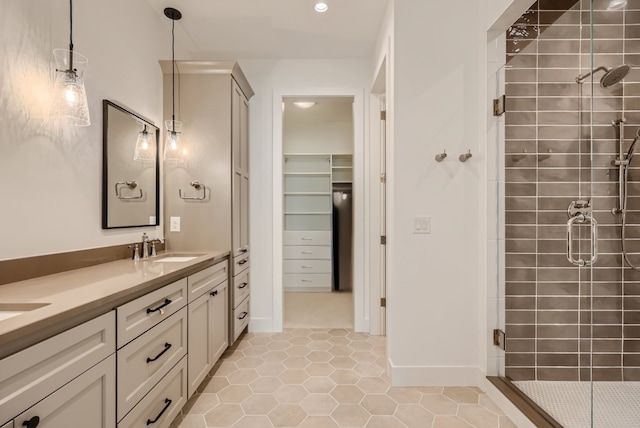 full bathroom with double vanity, a sink, a shower stall, tile patterned flooring, and baseboards