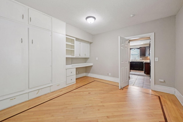 301 Lake St, Waconia, MN 55387 - unfurnished office featuring built in desk, baseboards, light wood finished floors, a textured ceiling, and a sink