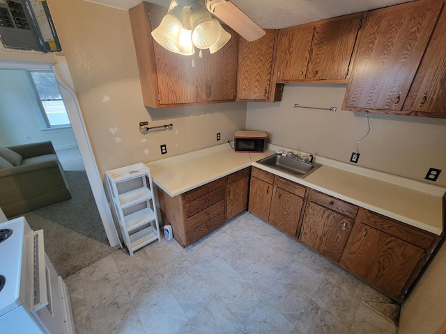 kitchen featuring light countertops, a sink, a ceiling fan, and brown cabinets