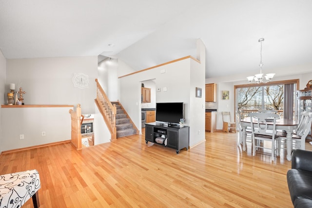 living area with baseboards, light wood-style flooring, stairs, high vaulted ceiling, and a notable chandelier