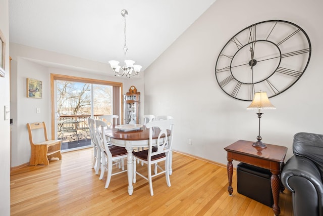 dining space featuring an inviting chandelier, vaulted ceiling, baseboards, and light wood finished floors